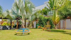 A well-maintained outdoor area with a swing set, a seesaw, and a small slide.
