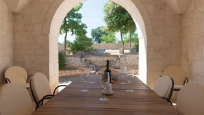 Un área de comedor al aire libre con un arco de piedra, una mesa de madera y varias sillas.