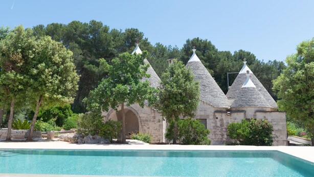 Un área de piscina con edificios de piedra y árboles.