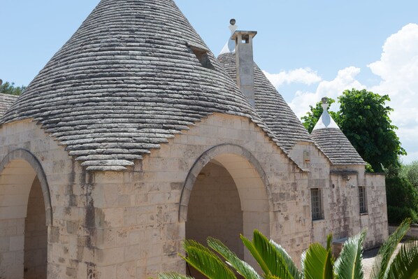 A stone building with a conical roof and arched doorways.