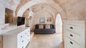 A room with stone walls, a sofa, a TV, and a cabinet.