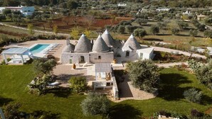 A villa with multiple conical-roofed structures, a swimming pool, and a well-maintained garden.