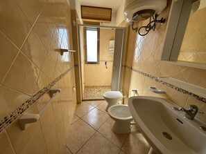 A bathroom with a bathtub, two toilets, and a shower area. - Appartamenti al mare Torre Pali (Salve)