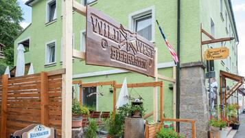 A green building with a sign that reads "Wild West Biergarten Pension".