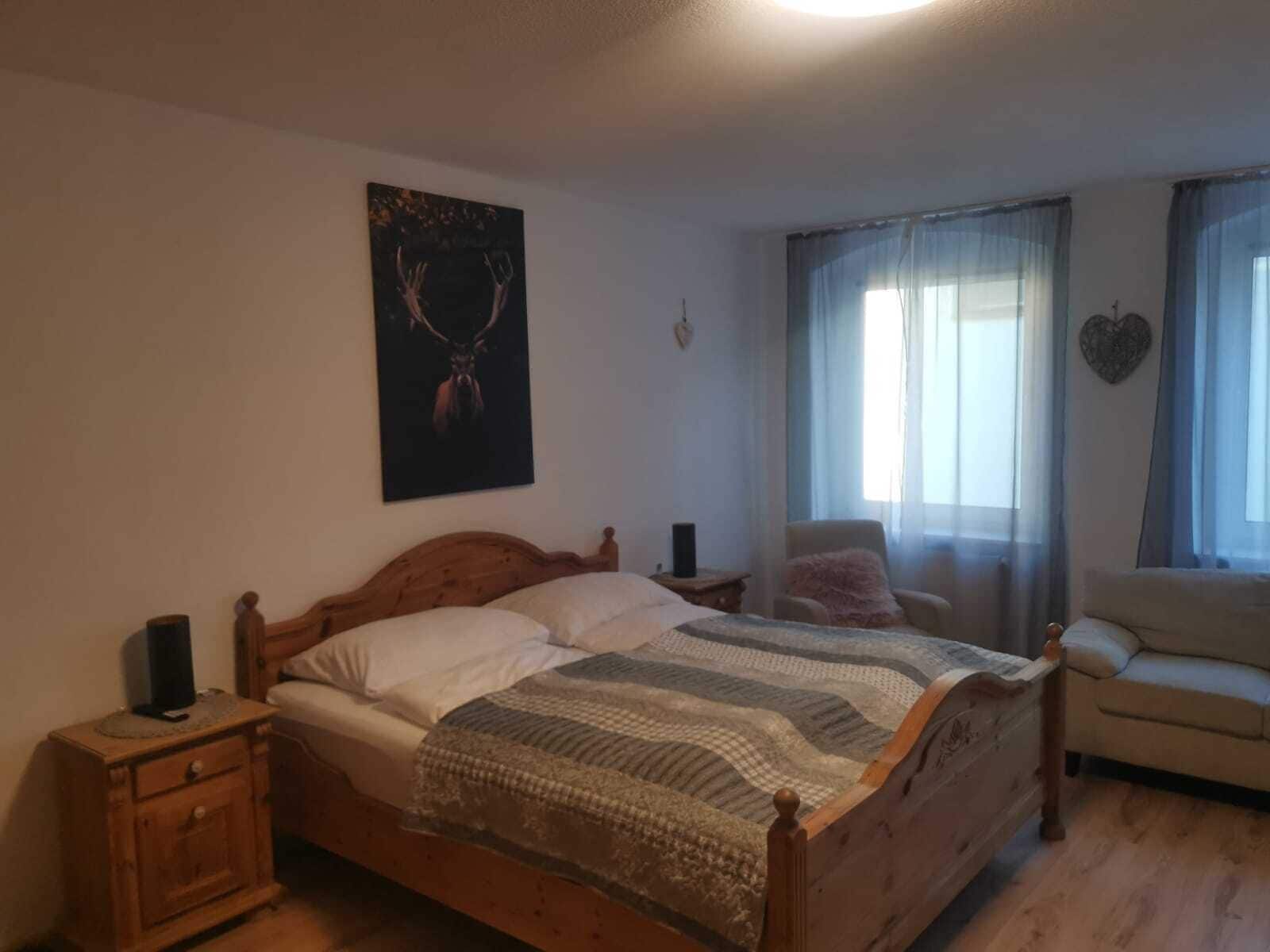 Une chambre à coucher avec un lit en bois, une table de chevet, une chaise et un canapé.