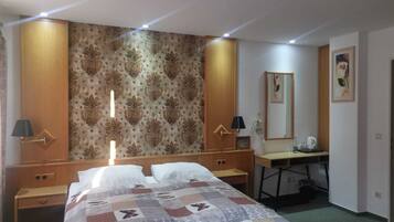 Ein Hotelzimmer mit Bett, Schreibtisch, Spiegel und Nachttisch.