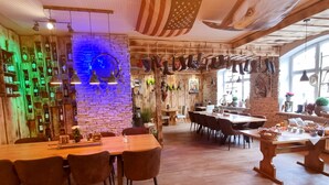 A restaurant with a rustic interior, featuring a brick wall, wooden ceiling, and a variety of hanging items.