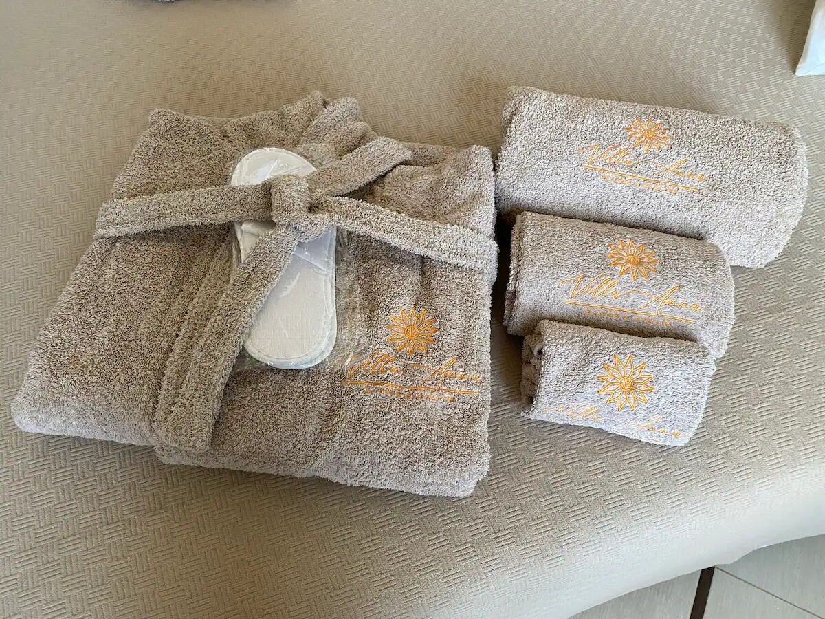 A set of towels with embroidered sun designs and a white plastic bottle.