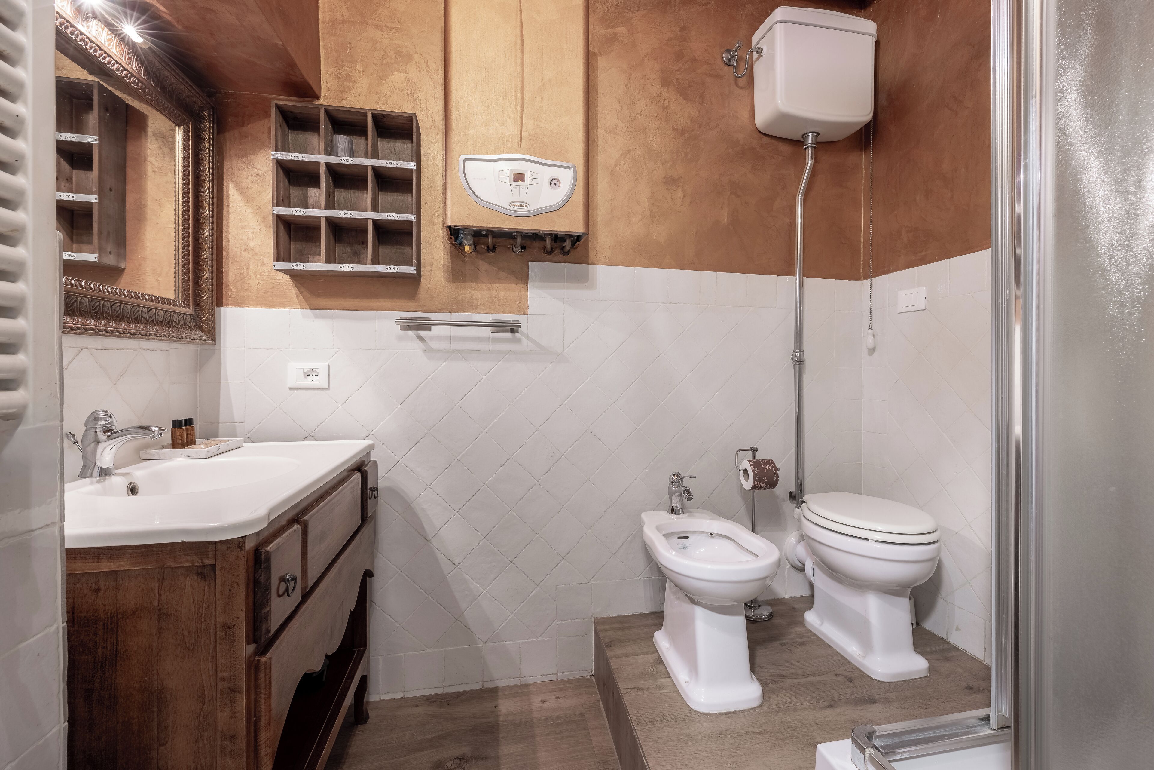 A bathroom with a wooden vanity, a toilet, a bidet, and a shower area.