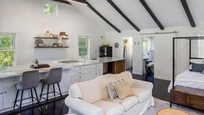 A modern interior with a kitchen, dining area, and a bedroom. - Cozy, private and modern Cottage (Hudson)