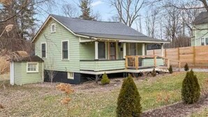 A single-story house with a porch, a small attached garage, and a fenced yard. - Cozy, private and modern Cottage (Hudson)