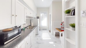 Een moderne keuken met witte kastjes, een zwarte magnetron en een RVS spoelbak.