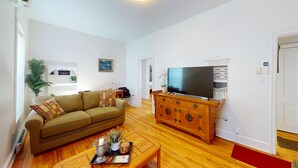 Een woonkamer met een bank, salontafel, televisie en een houten kast.