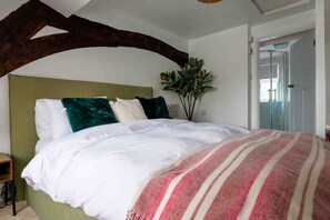 A bedroom with a bed, a green headboard, and a plant. - Cosy 1 bedroom cottage in The Cotswolds (Chipping Norton)