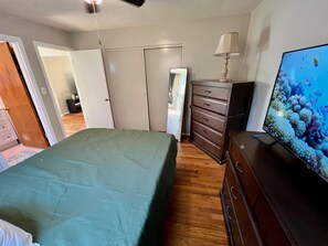 Ein Schlafzimmer mit Bett, Kommode, Fernseher und Deckenventilator.