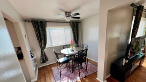 A dining area with a round table, chairs, a ceiling fan, and a TV stand.