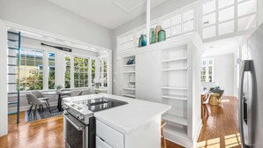 A modern kitchen with white cabinetry, a built-in stove, and a dining area with a table and chairs. - Pet Friendly, 150 Yards to Pool, 1 Min to the Beach, Shopping and Dining (Santa Rosa Beach)