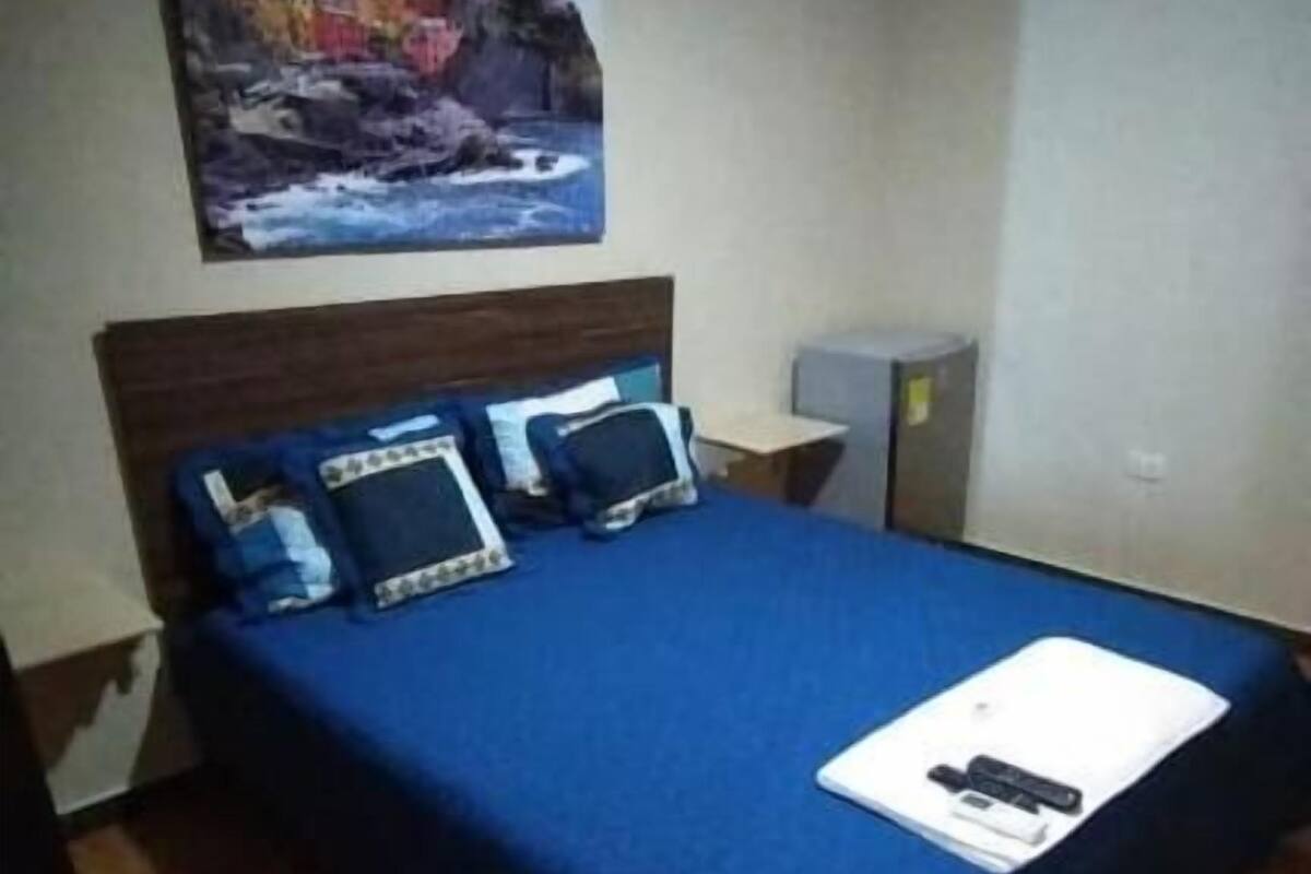 Una camera da letto con un letto, un comodino, un quadro e una scrivania.