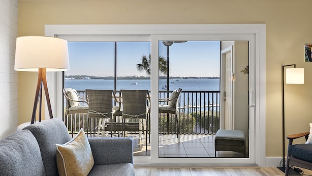 Habitación con sofá, lámpara y vista al mar a través de una puerta corrediza de vidrio.