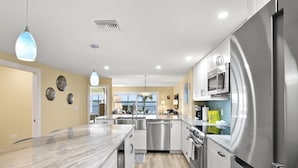 Una cocina moderna con electrodomésticos de acero inoxidable, encimera de mármol e iluminación colgante.