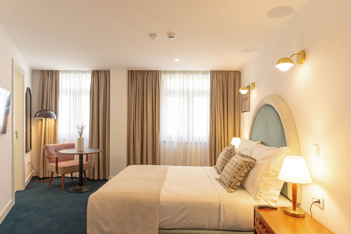 Una habitación de hotel con cama, escritorio, silla y lámpara.