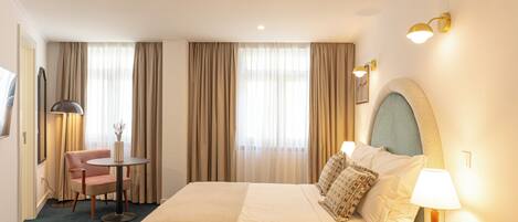 Quarto de hotel com cama, escrivaninha, cadeira e abajur.