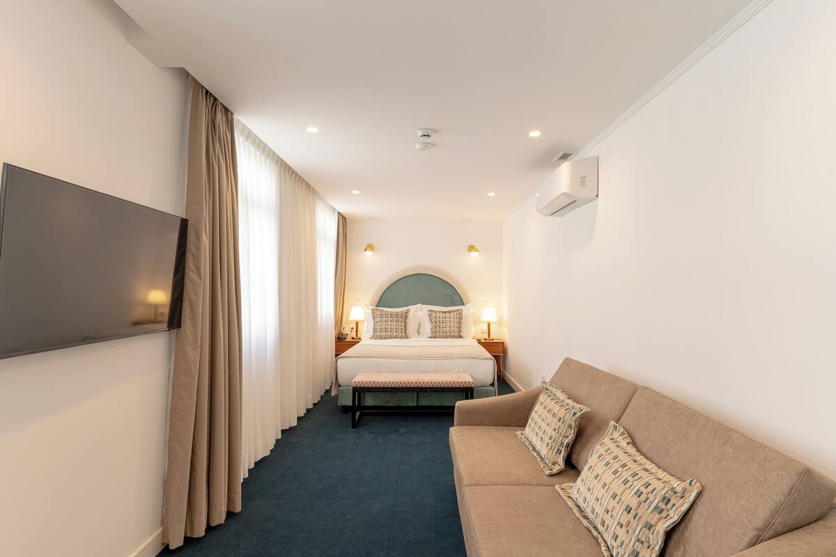 Habitación de hotel con cama, televisión, sofá y una escalera que lleva a otra habitación.