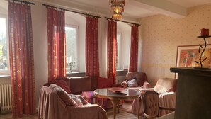 Un salon chaleureux avec un canapé, des fauteuils, une table ronde et une cheminée.