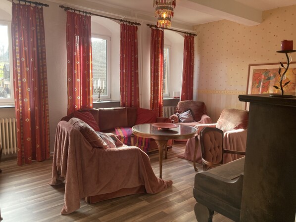 Una sala de estar acogedora con un sofá, sillones, una mesa redonda y una chimenea.