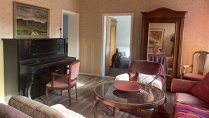 Un salon avec un piano, une table en verre et un canapé.