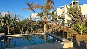 A pool area with palm trees and cacti, surrounded by modern buildings. - Condo#2-5Min Walk to Beach/Surf-Sleeps2-KingSuite (Los Cerritos)