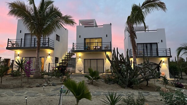 A modern two-story building with balconies, surrounded by cacti and palm trees. - Condo#2-5Min Walk to Beach/Surf-Sleeps2-KingSuite (Los Cerritos)