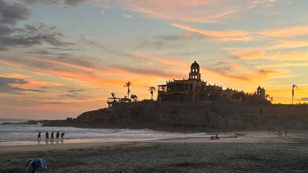 A beach with a historic building on a hill, people walking, and a chair on the sand. - Condo#5- 5 Min Walk2Beach/Surf-Sleeps4-Queen Suite (Los Cerritos)