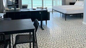 Une chambre d’hôtel avec un lit, un bureau, une chaise, une télévision et une vue sur l’océan.