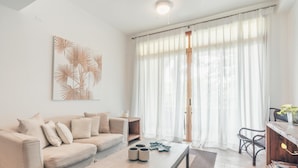 Een moderne woonkamer met een beige bank, een salontafel en een eethoek met een houten tafel en stoelen.