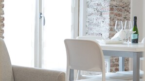 A dining area with a white table and chairs, a brick wall, and a bottle of champagne. - Milano Suite Home - Your home in Milan! (Milano)
