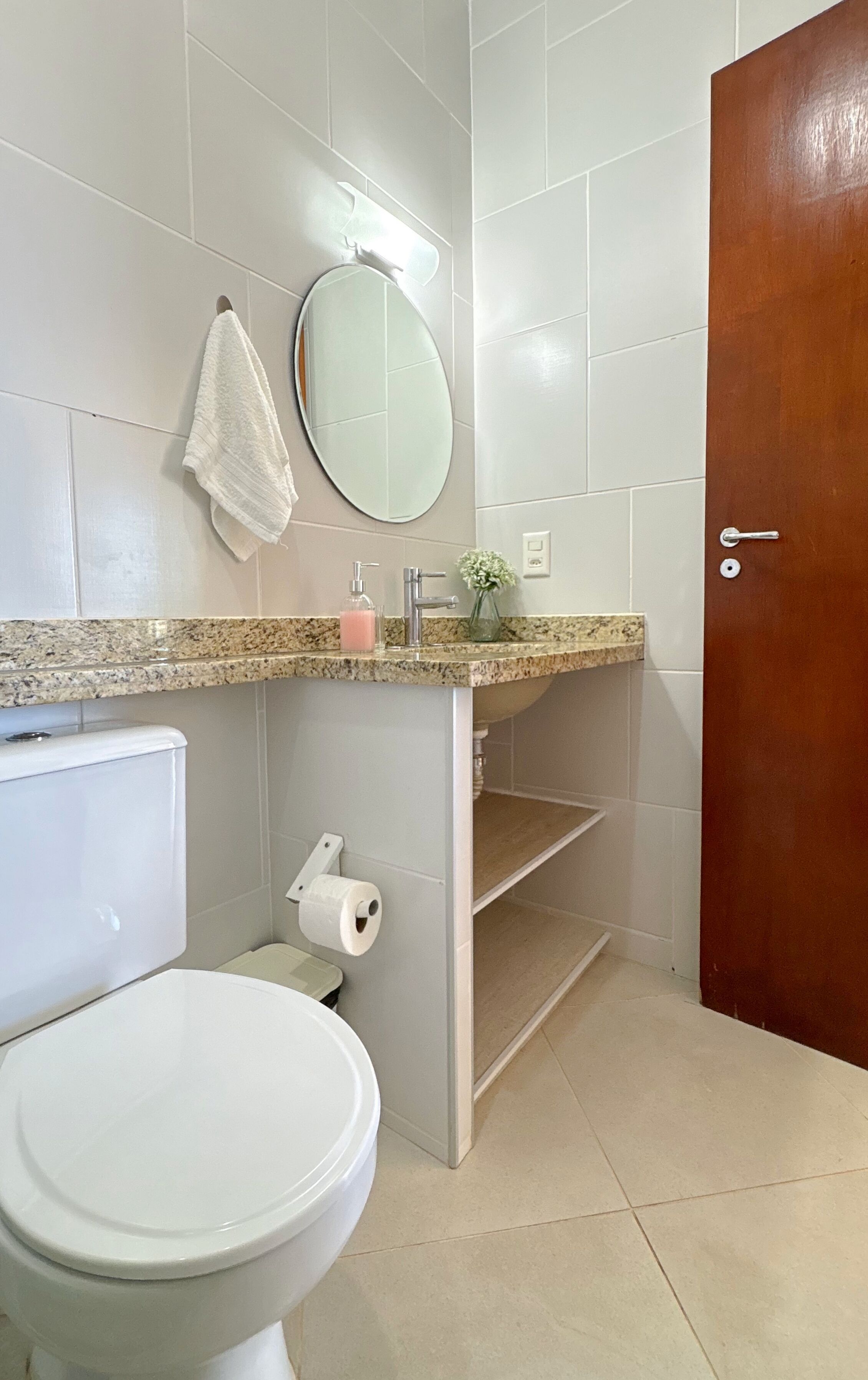 A bathroom with a toilet, sink, mirror, towel, and a wooden door.