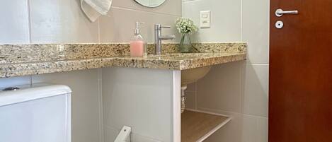 A bathroom with a toilet, sink, mirror, towel, and a wooden door.
