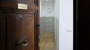 Une porte en bois avec une plaque nominative, une horloge au mur et un interrupteur.