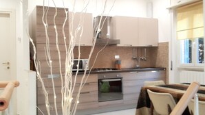 Una cocina moderna con armarios de madera, horno empotrado y comedor con mesa y sillas.