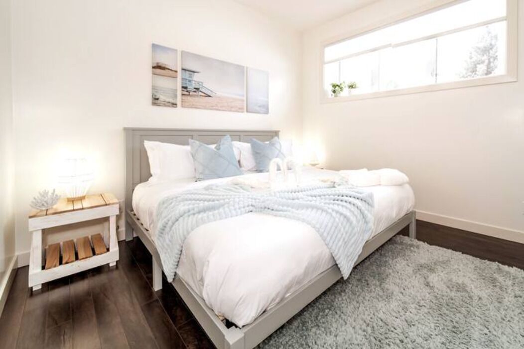 A bedroom with a bed, a nightstand, a window, and wall art.