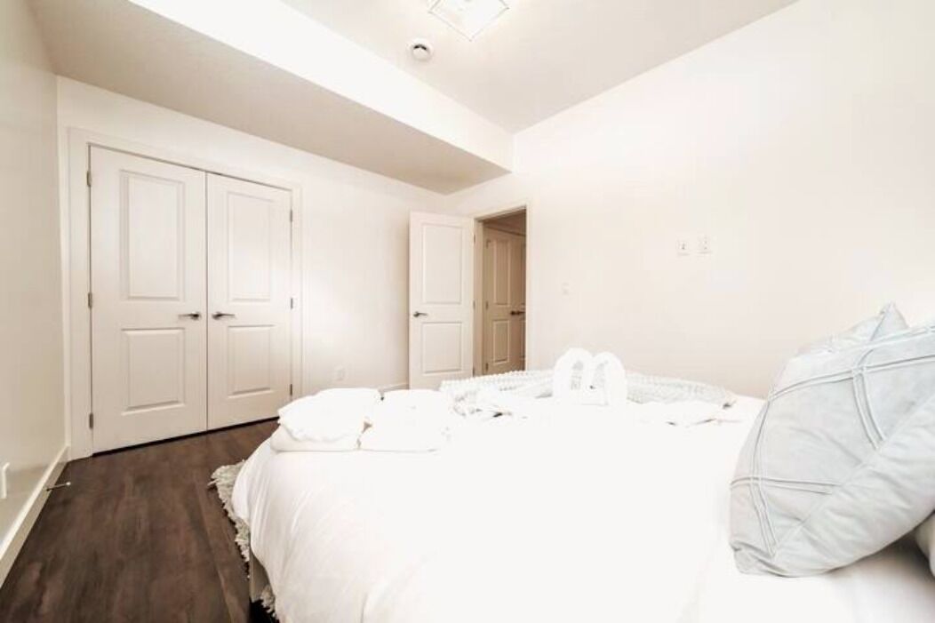 A bedroom with a large bed, two white doors, and a skylight.