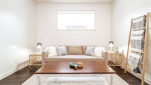 A living room with a beige sofa, two side tables with lamps, a wooden coffee table, and a woven basket.