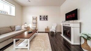 A living room with a sofa, coffee table, fireplace, and a TV mounted on the wall.