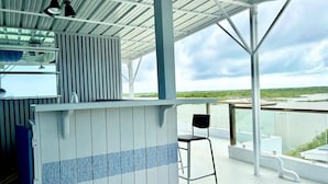 A covered outdoor area with a bar counter and a single black chair.