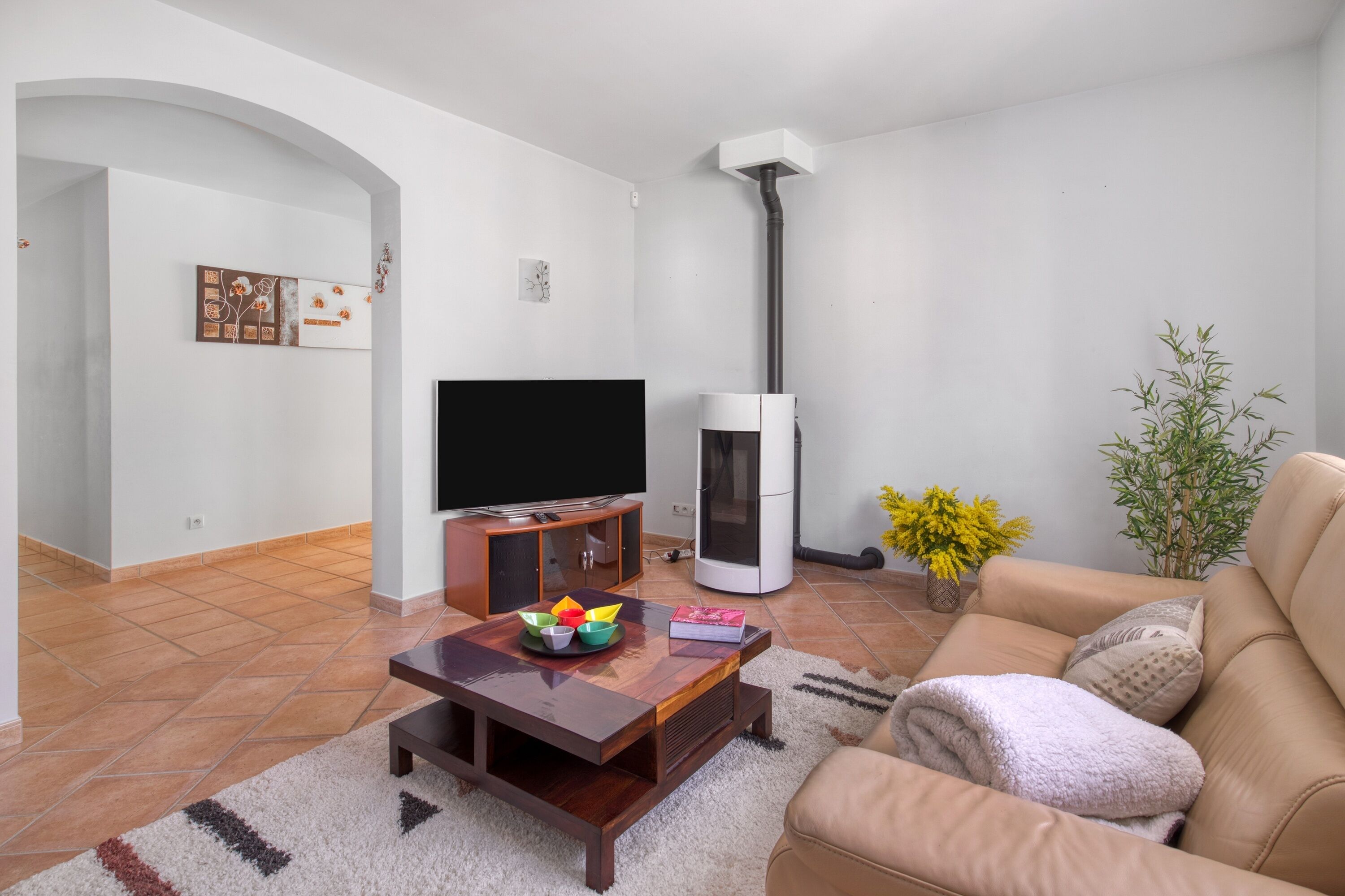 Una sala de estar con televisor, chimenea, sofá y mesa de centro.