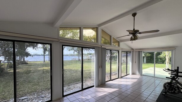 A spacious room with large sliding glass doors leading to a backyard with a view of a lake.