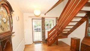 A staircase with wooden railings leading to a landing, a wooden floor, a large wall clock, and a door with glass panels. - Glyde House (Dorchester)
