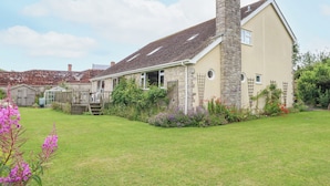 A stone house with a chimney, a small garden with flowers, and a grassy lawn. - Glyde House (Dorchester)