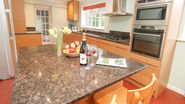 A modern kitchen with granite countertops, stainless steel appliances, and wooden cabinetry. - Glyde House (Dorchester)